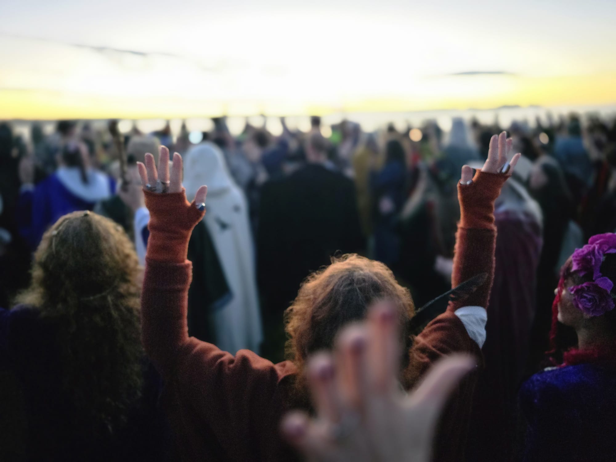 Hands raised at dawn during a gathering
